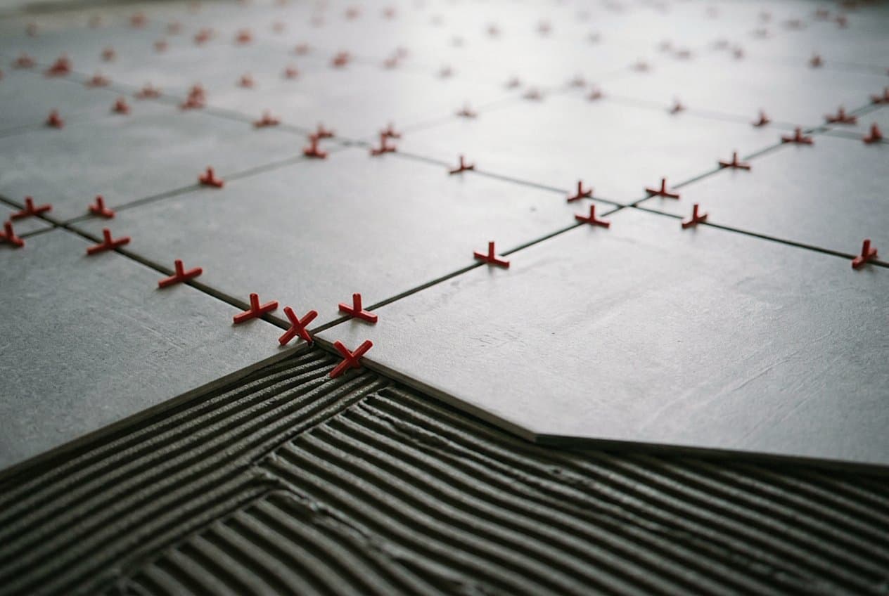 Red spacers marking joints on large floor tile