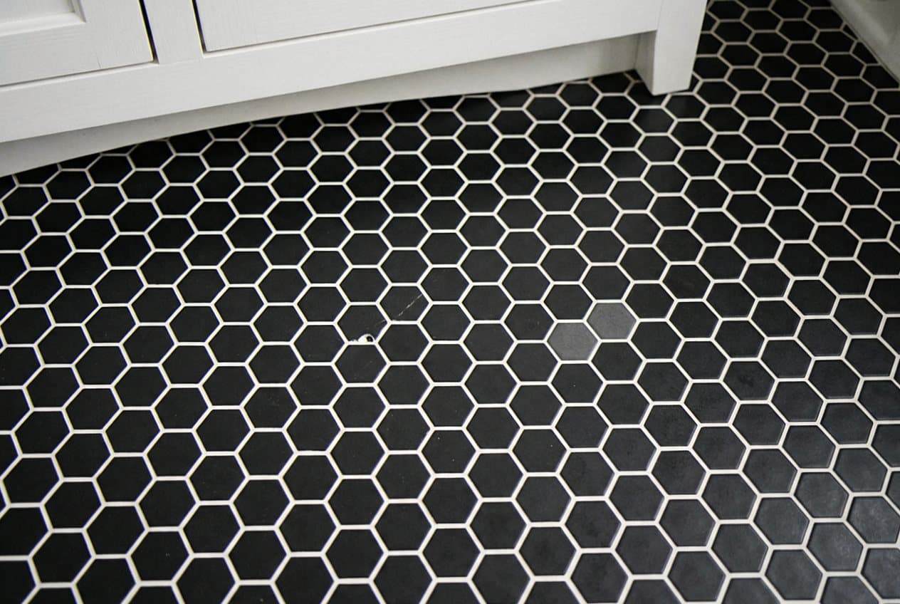 Black hexagon mosaic floor tile by a vanity
