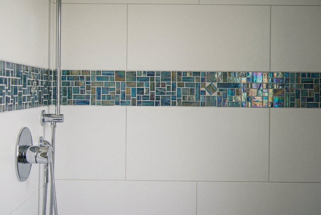 Iridescent glass mosaic accent stripe in a shower