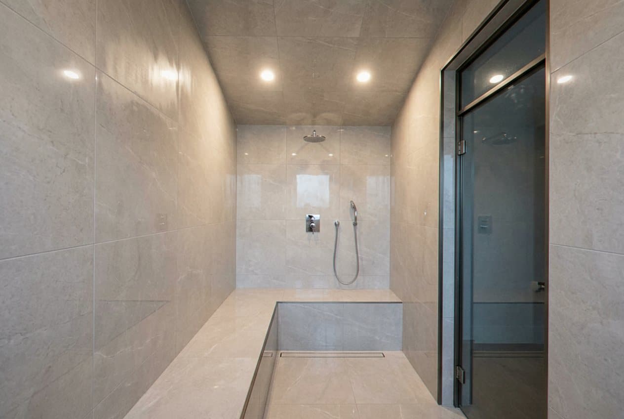 Large tiled steam shower with glass door and bench